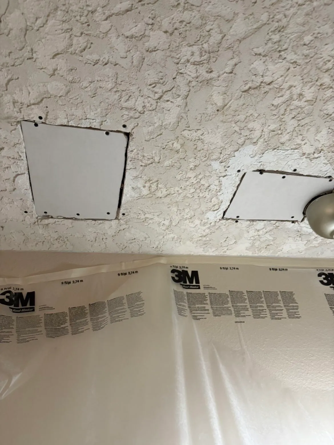 Two kitchen ceiling patches near a light fixture before mudding, drywall replaced and ready for finishing