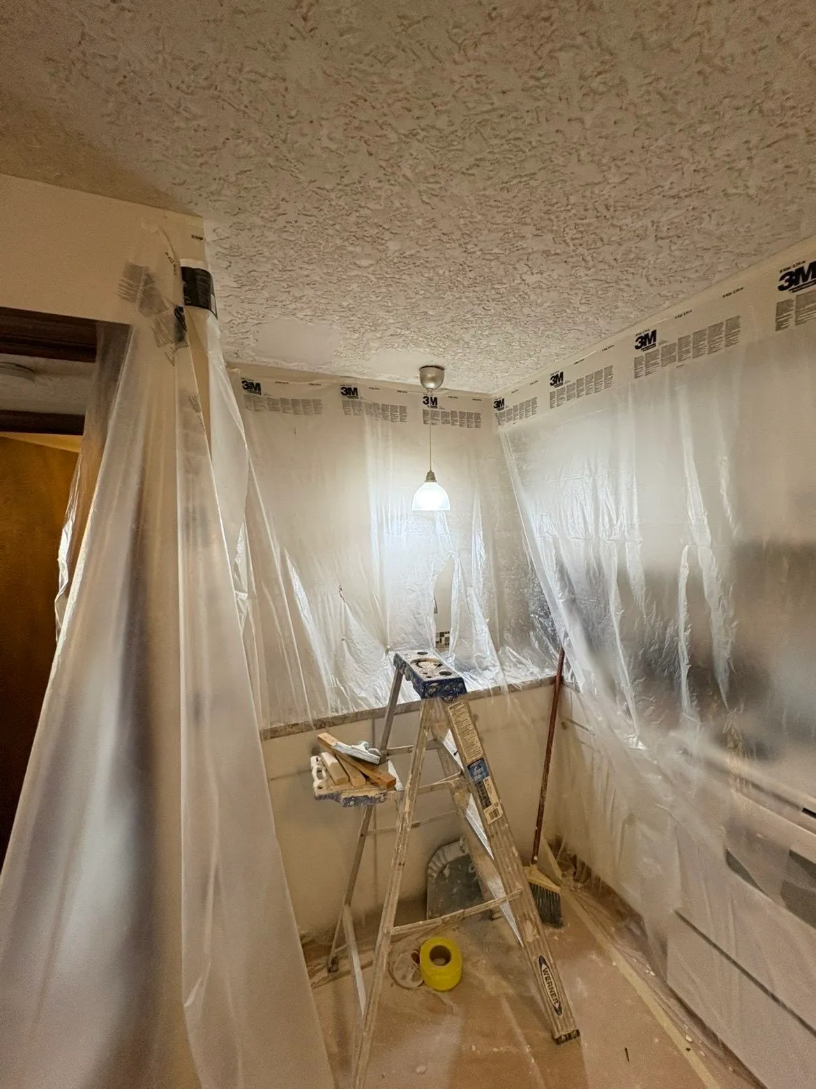 Joint compound smoothed over kitchen ceiling patches around light fixture
