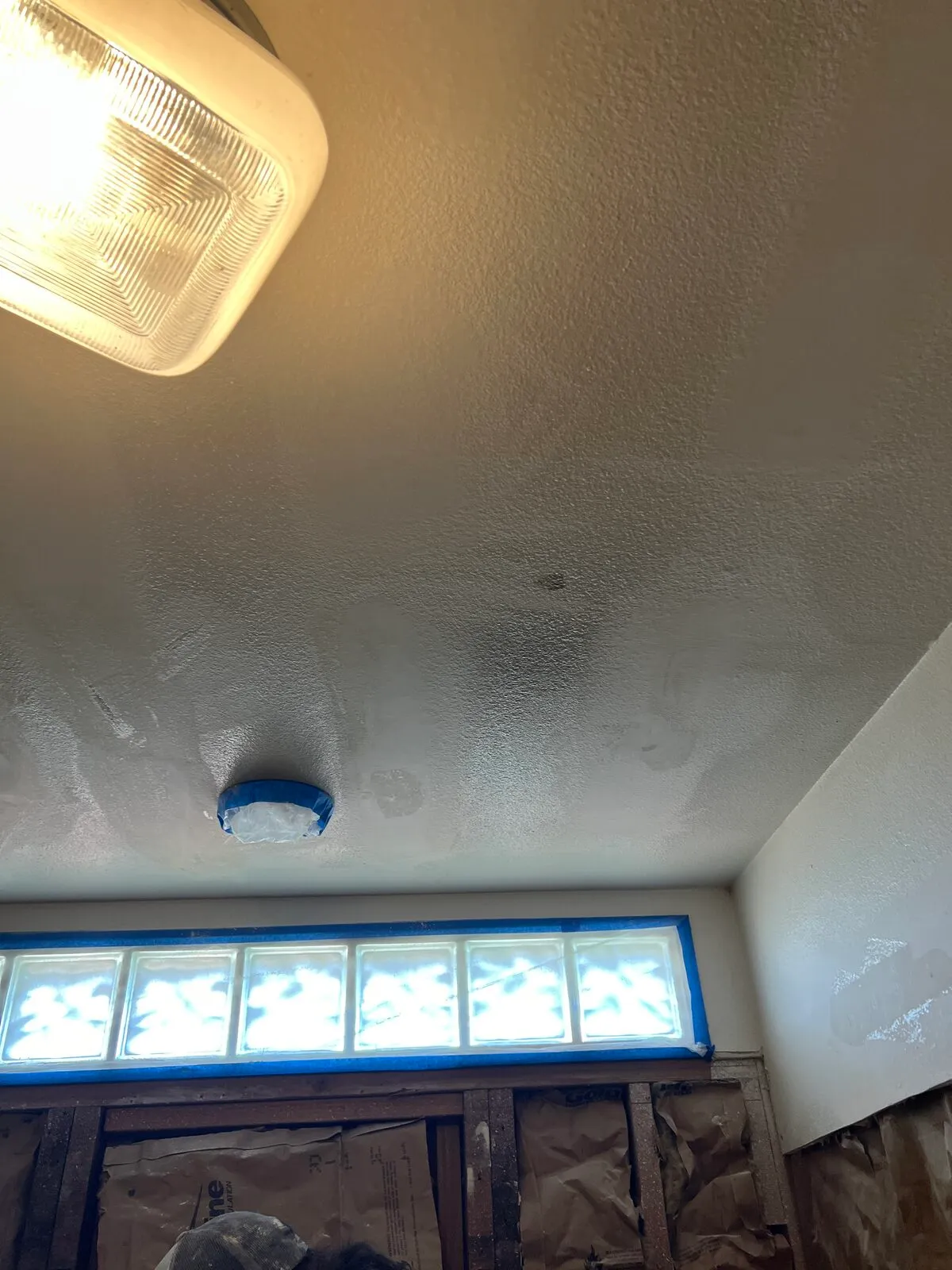 Masked ceiling light fixture during bathroom drywall work
