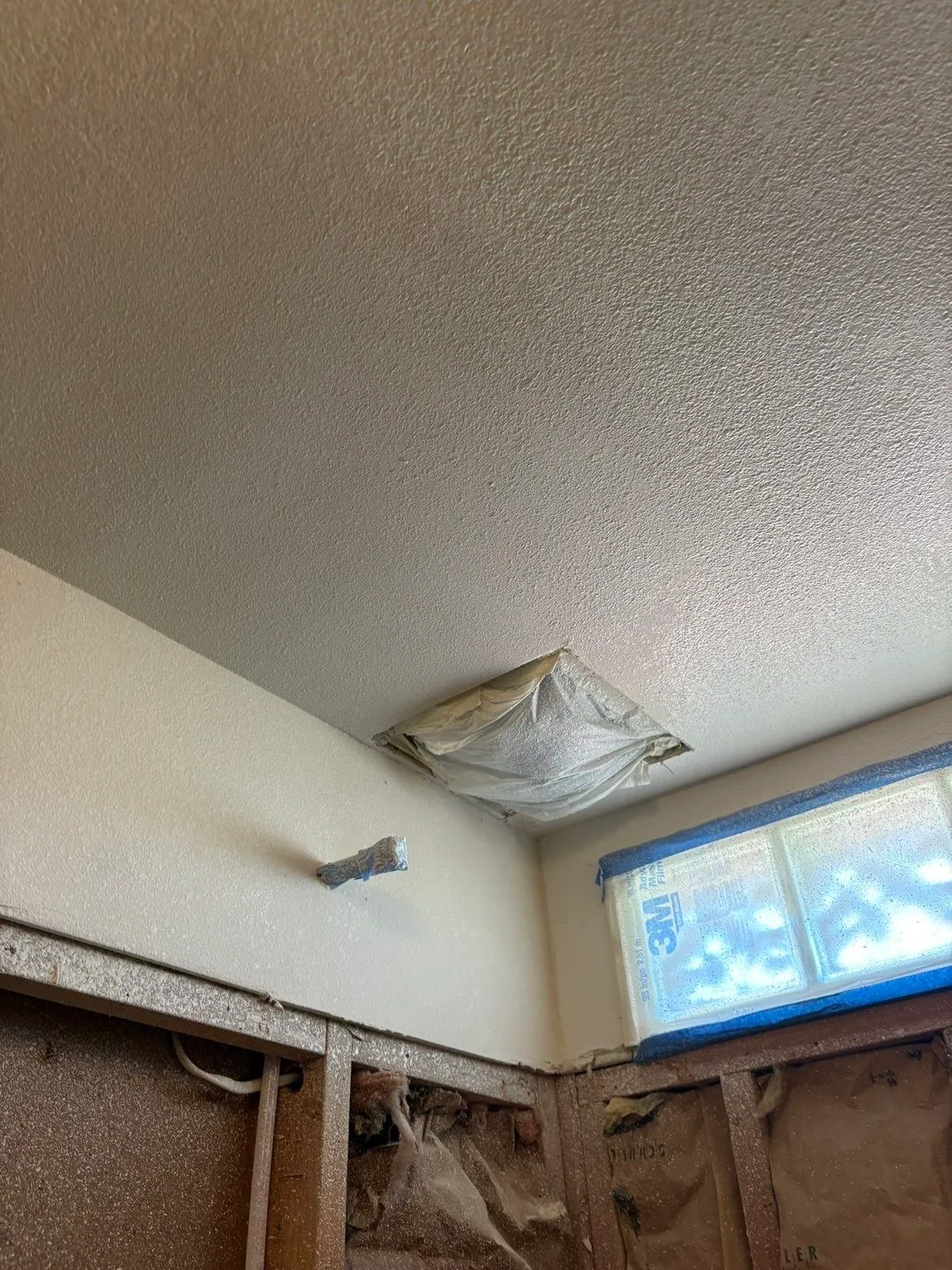 Masked air vent and ceiling patch during bathroom drywall work, dust protection setup