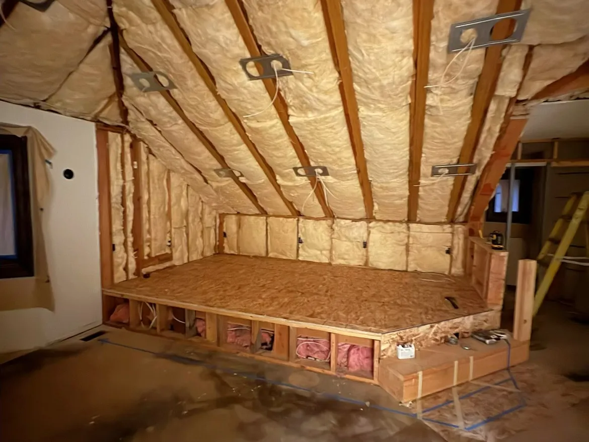 Attic bonus room with batts between the rafters on the sloped ceiling and insulated knee walls before drywall