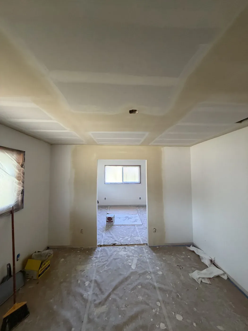 New drywall ceiling overlay with taped seams above protected floors and windows in Vancouver, Washington