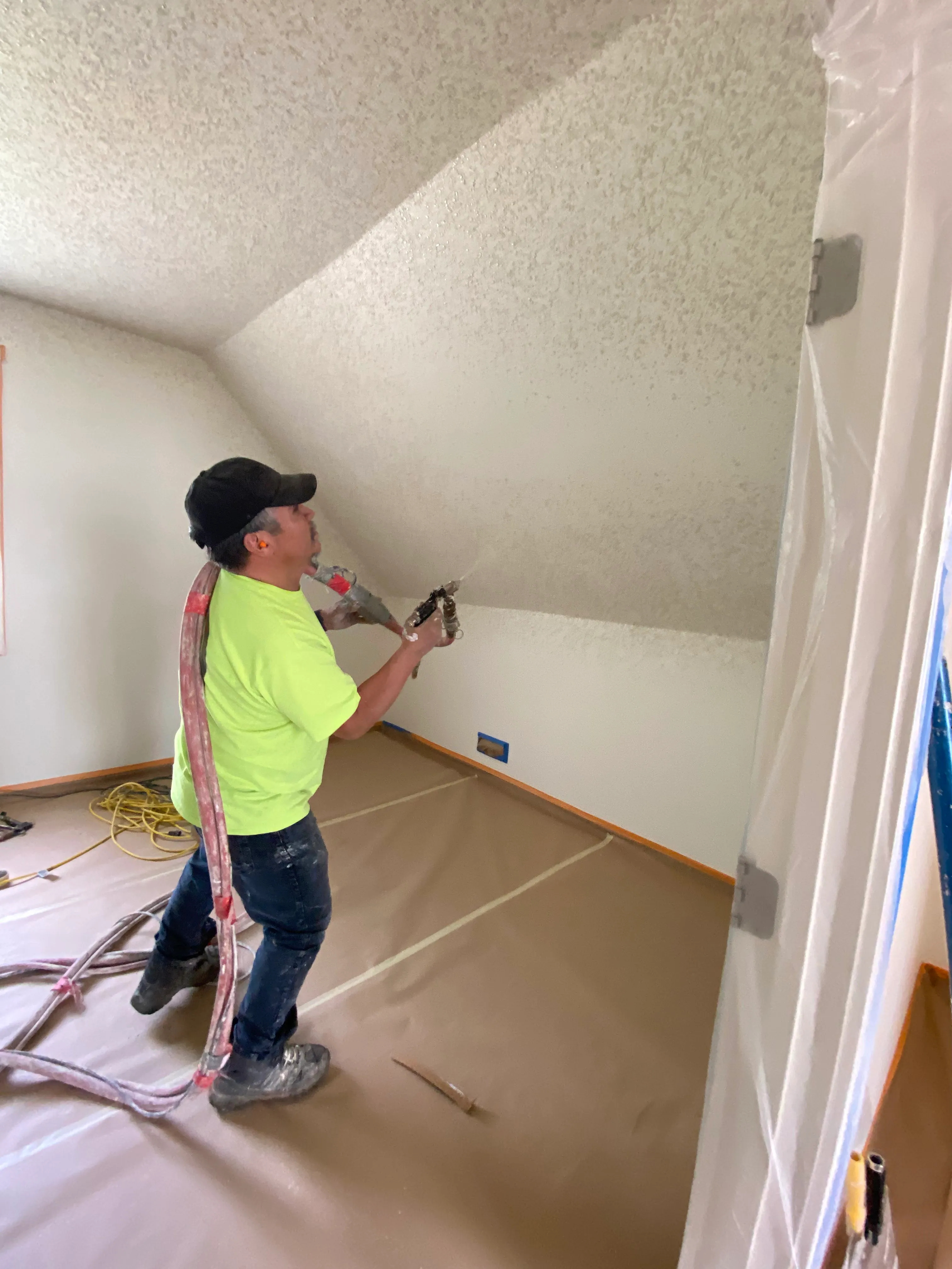 AvilaCo crew member spraying knockdown texture on vaulted ceiling walls