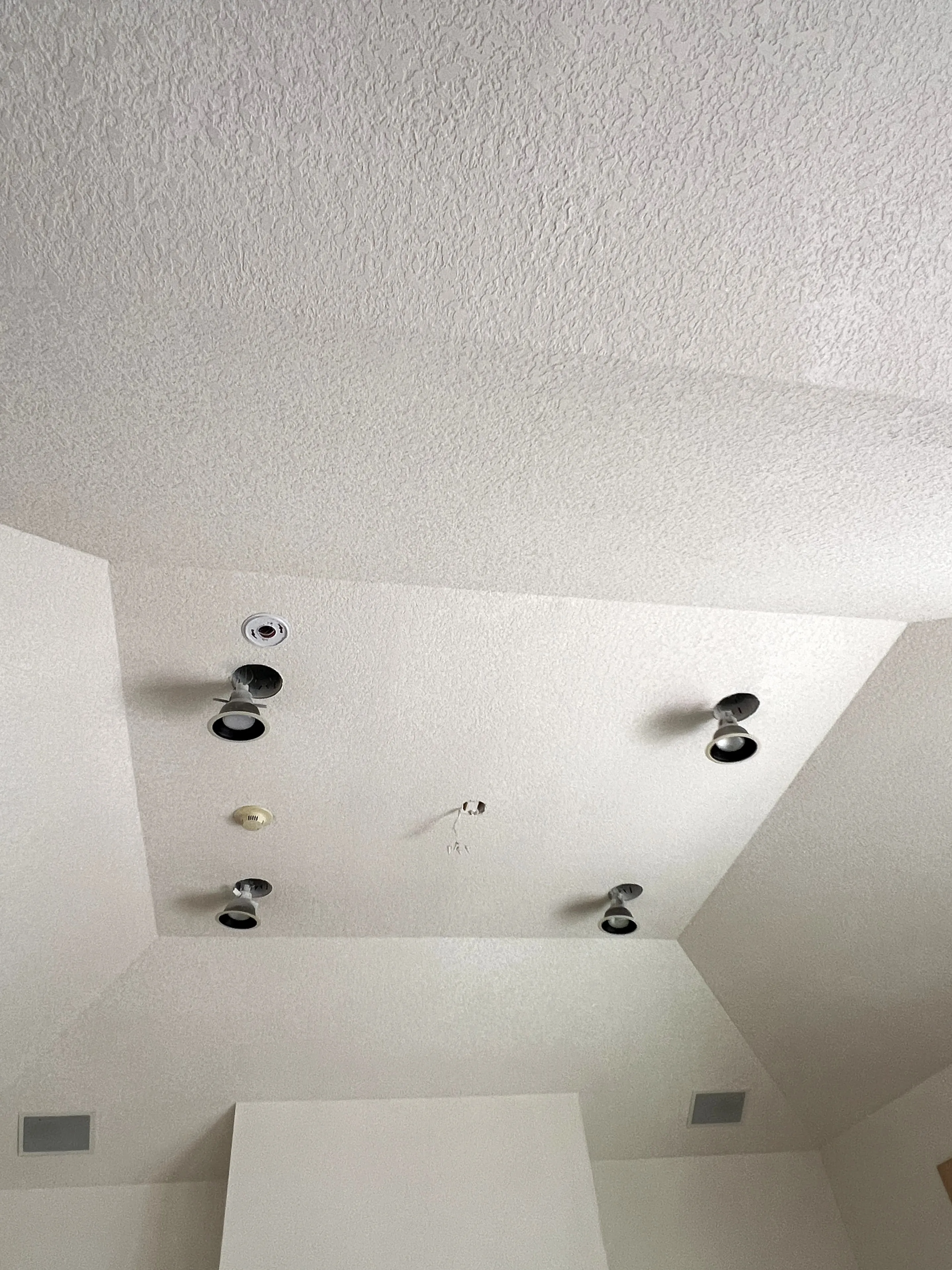 Textured ceiling drywall installation with recessed lighting cutouts
