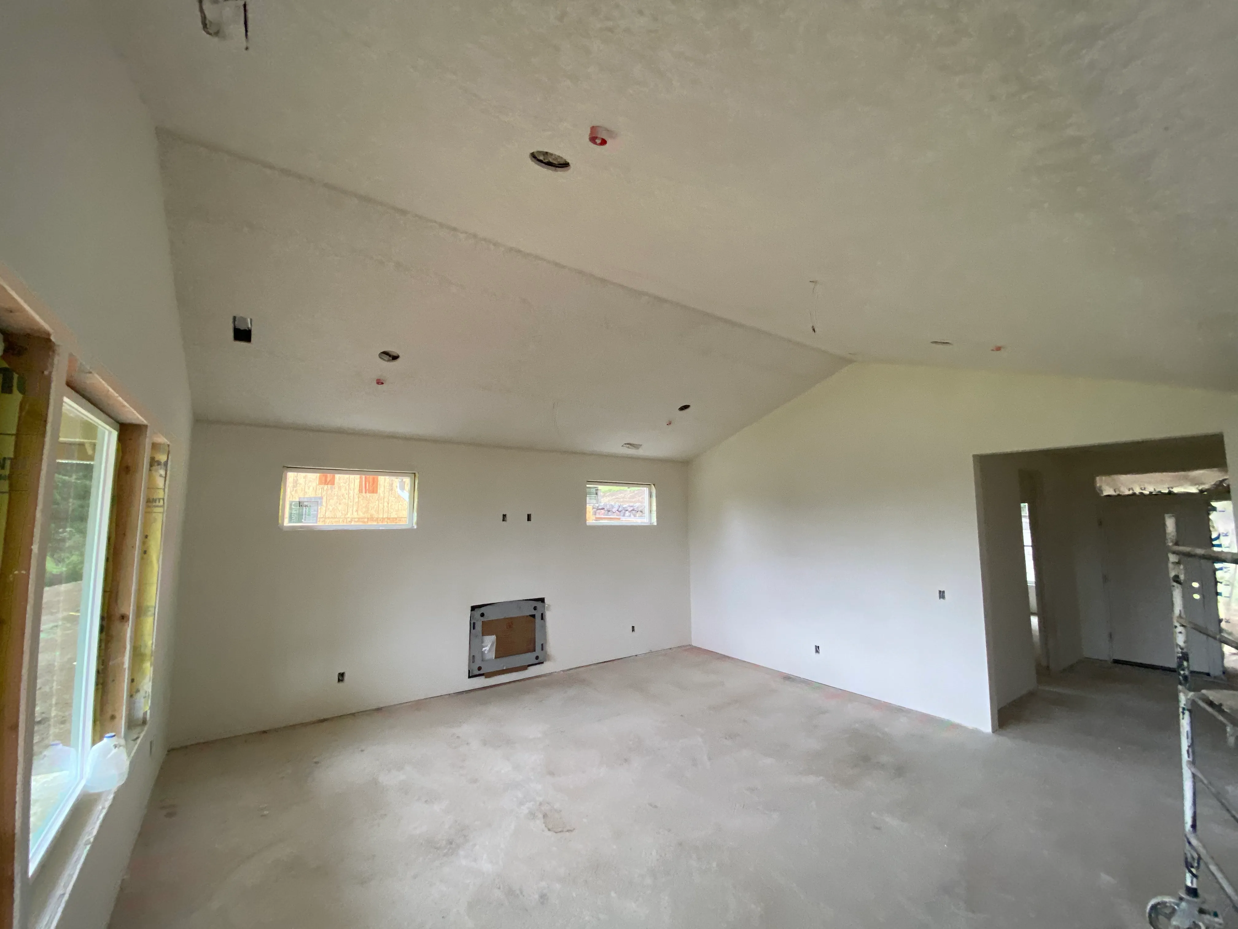 Living room drywall installation with fireplace cutout and textured ceiling