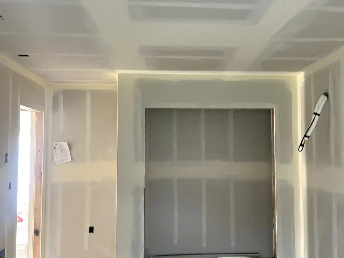 Recessed wall niche framed for a media wall, with the room taped and mudded around recessed lights and a stepped ceiling detail