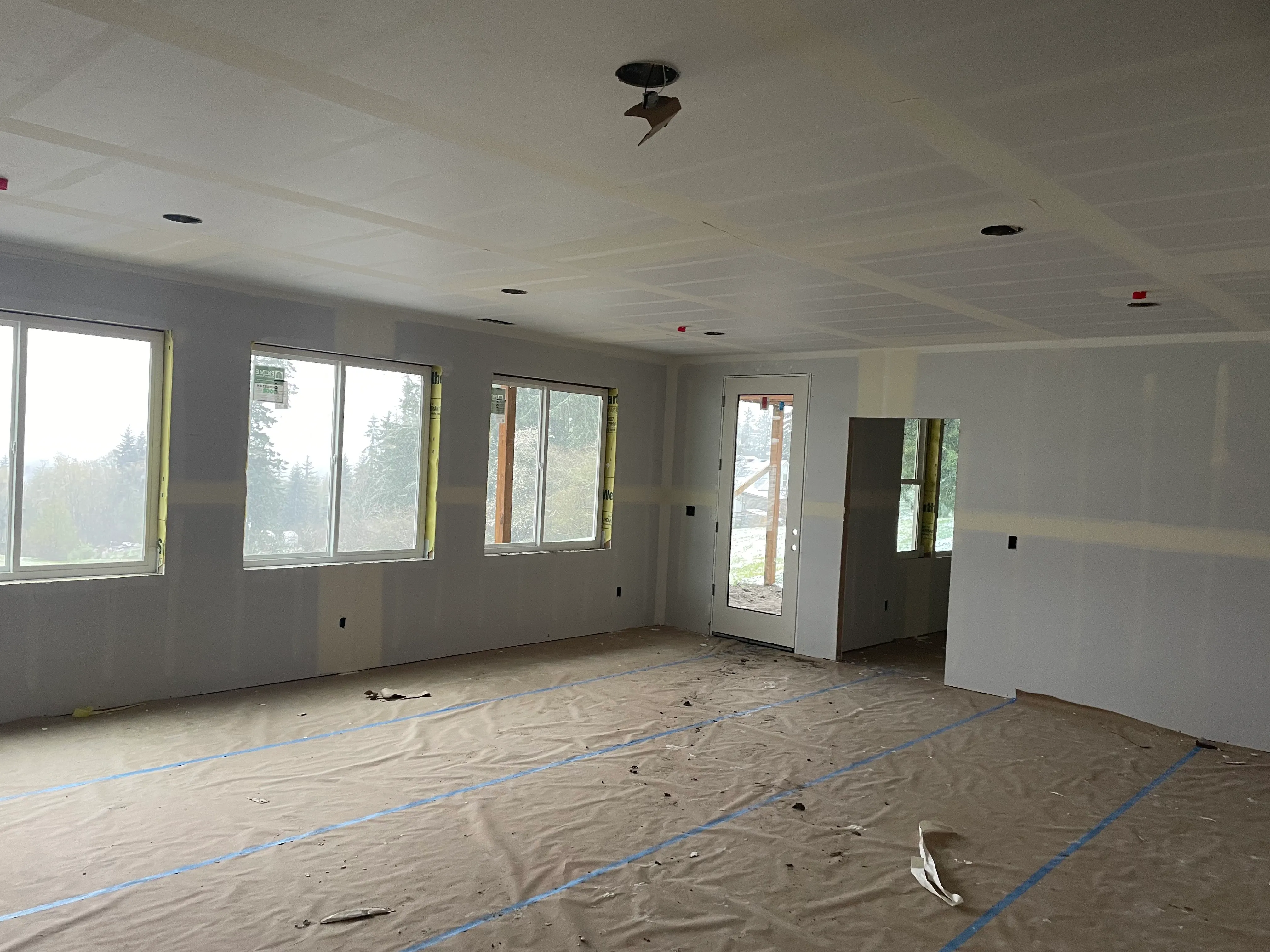 Open living area with freshly hung drywall panels and recessed lighting cutouts