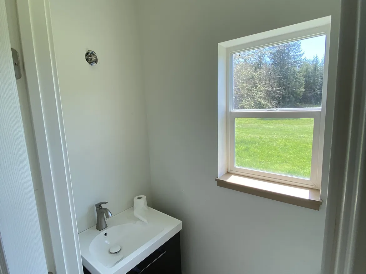 Small finished half bath seen through the doorway with smooth painted walls, a window onto a lawn and trees, and a floating vanity